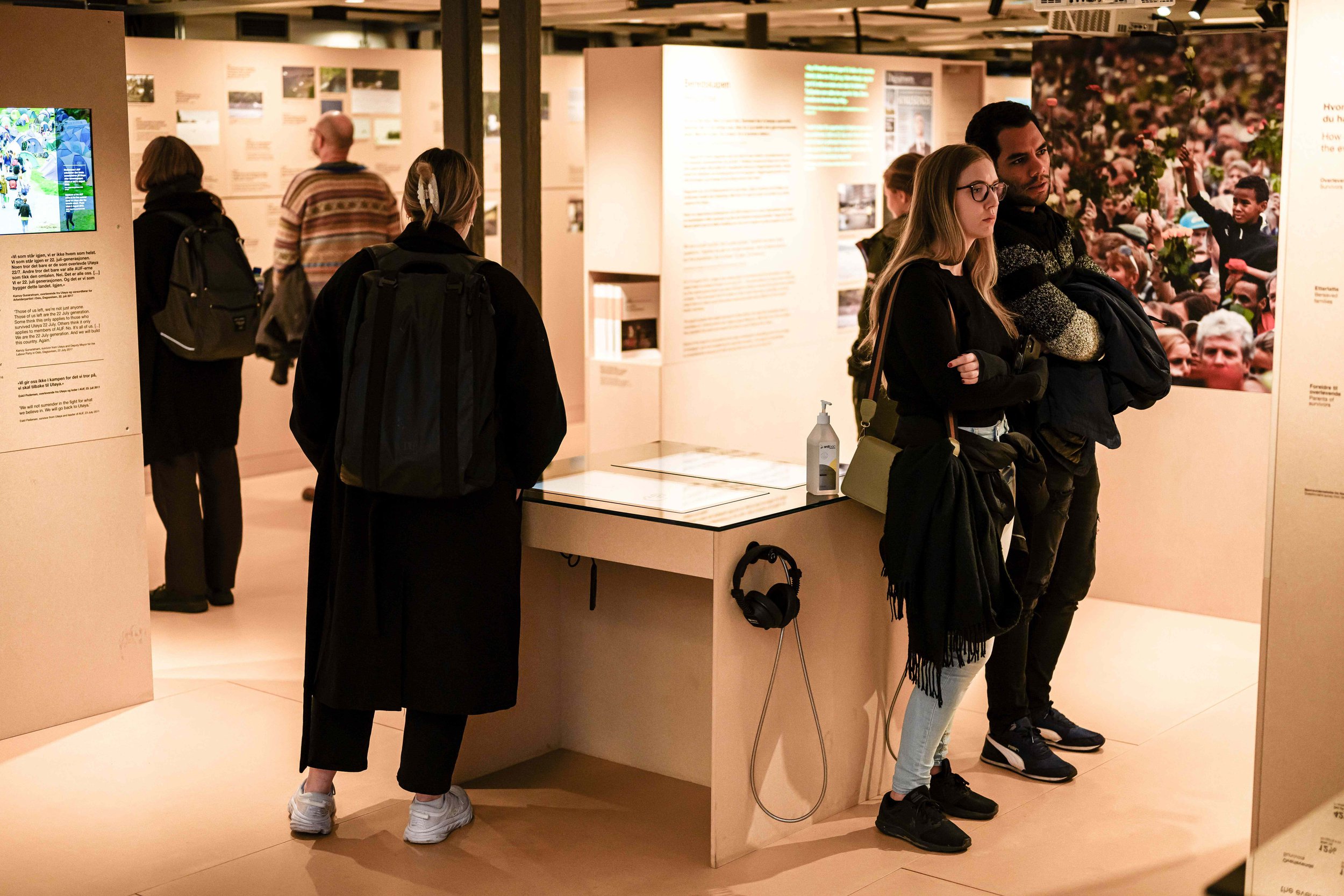 Seks personer står på et museum og ser på ulike utstillinger. Fire står med ryggen til.