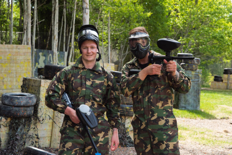 to menn i kamuflasjeklær på paintball bane.