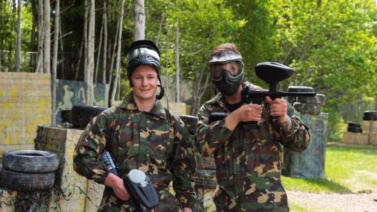 to menn i kamuflasjeklær på paintball bane.