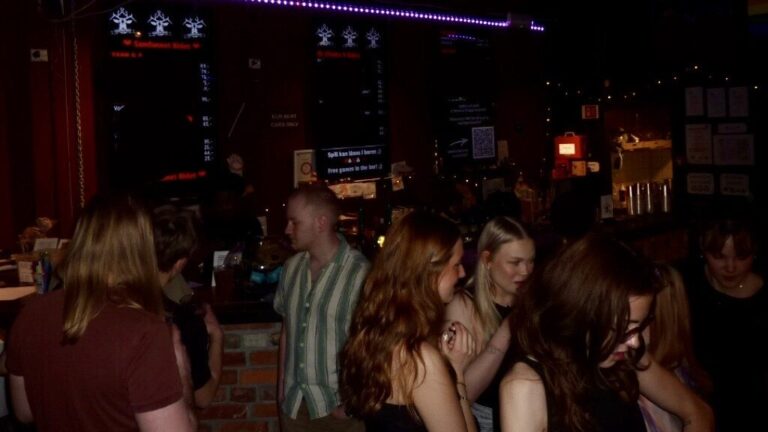 folk som danser og snakker i mørkt barlokale.