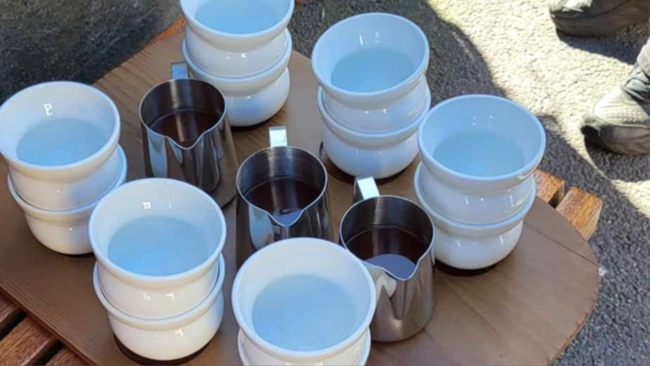 hvite kaffekopper og stålkanner på en trefjøl.
